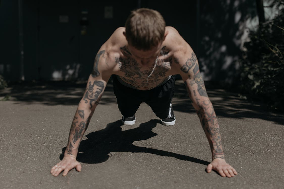 A tattooed guy doing push-ups