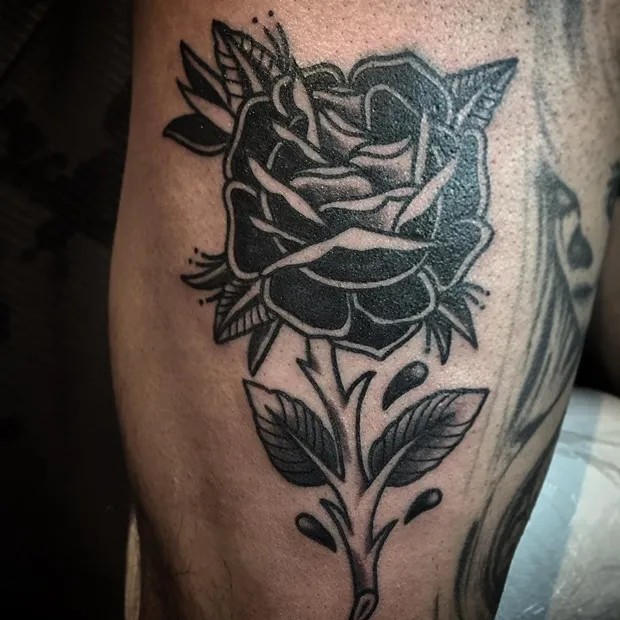 Black rose tattoo on a man's lag