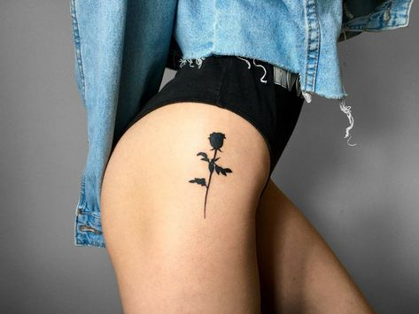 Black rose tattoo on a woman's thigh