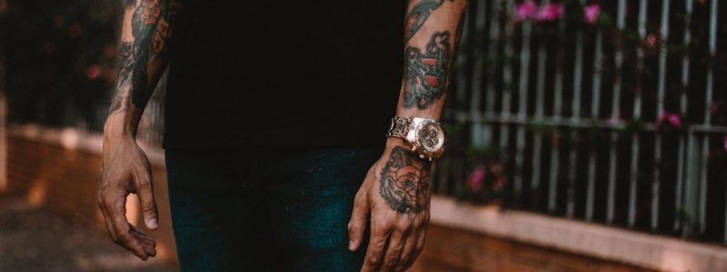 A man with tattoed forearms and a watch